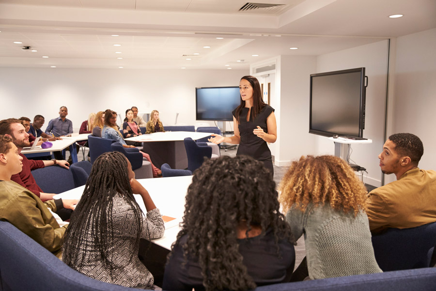 Female teacher addressing students in a classroom.